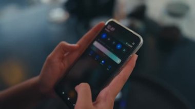 Kafedeki arkadaşından gelen bir mesajı okurken elinde akıllı bir telefon tutan bir kadın.