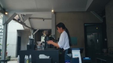 Kafe mutfağında elinde üzgün bir ifadeyle akıllı bir telefon tutan bir kadın.