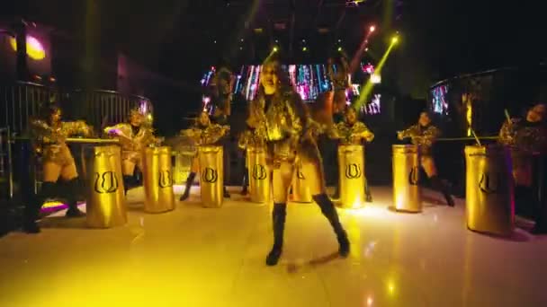 一个亚洲女人 穿着金色的自由舞服装 站在她朋友面前 她在舞台上打鼓 — 图库视频影像