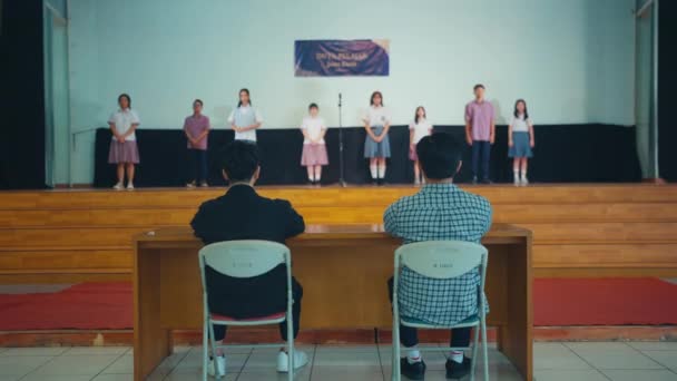 当一群学生站在舞台上时 他们从学校大厅里的法官那里得到了这个通知 — 图库视频影像