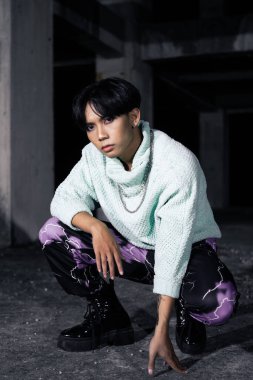 Siyah saçlı Asyalı bir adam eski bir binada çok erkeksi duruyor.