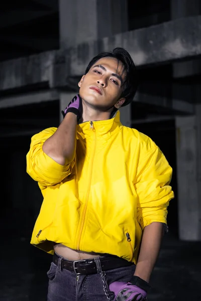 一个亚洲男人 穿着一件黄色的夹克 一头乌黑的头发 非常勇敢地摆设在一座废弃的大楼里 — 图库照片