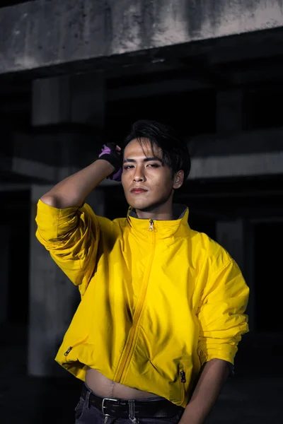 一个亚洲男人 穿着一件黄色的夹克 一头乌黑的头发 非常勇敢地摆设在一座废弃的大楼里 — 图库照片