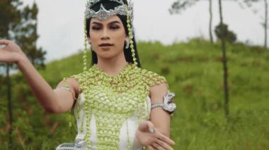 Süslü, geleneksel kostümlü bir dansçı yavaş, zarif ve geniş kol hareketleriyle gösteri yapar. Güzel doğal ortamdaki zarif koreografi efsanevi bir sanatçılık ve performans sahnesi yaratıyor..