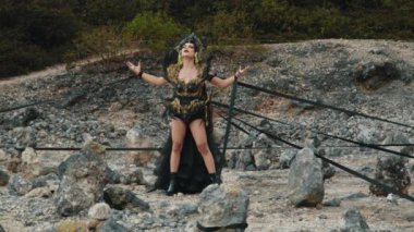 Büyücünün, bir büyüyü gerçekleştirirken yoğun, açık ağızlı bir ifadeyle orta boy yakın çekimi. Dramatik kostümü, başlığı ve koyu makyajı güçlü ve büyülü atmosferi güçlendiriyor..