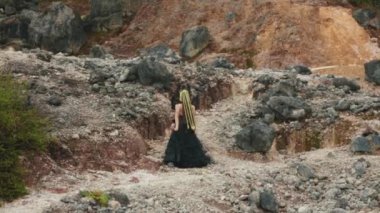 Karanlık fantezi kostümlü mistik bir kraliçe kayalık, kızıl toprak kanyonunda güçlü bir dans ritüeli gerçekleştiriyor. Kadim ruhları ya da doğal güçleri çağırır gibi ellerini göğe kaldırıyor..