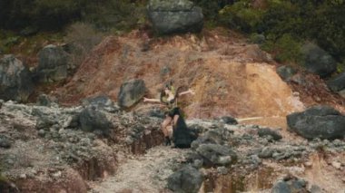 Büyüleyici siyah ve altın kostümlü güçlü bir kraliçe kayalık bir kanyonda duruyor ve el hareketlerini yönetiyor. Elementleri kontrol ediyor ya da tebaasına fantezi dünyasında hitap ediyor gibi görünüyor..