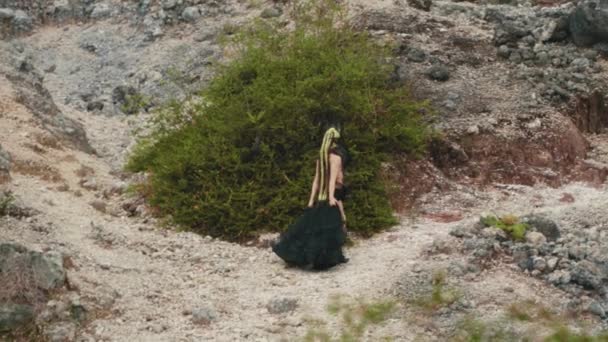 早朝岩だらけの山を歩く黒いドレスの魔女 — ストック動画