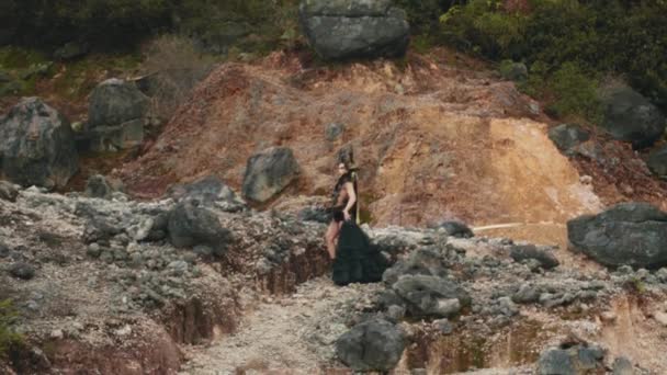 早朝岩だらけの山を歩く黒いドレスの魔女 — ストック動画