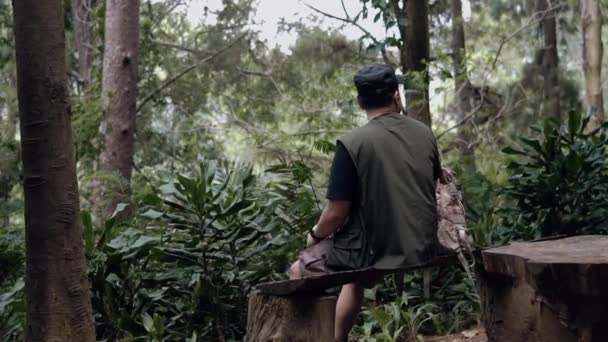 Азіатський Чоловік Чорному Капелюсі Сидить Дерев Яному Стільці Насолоджуючись Пейзажами — стокове відео