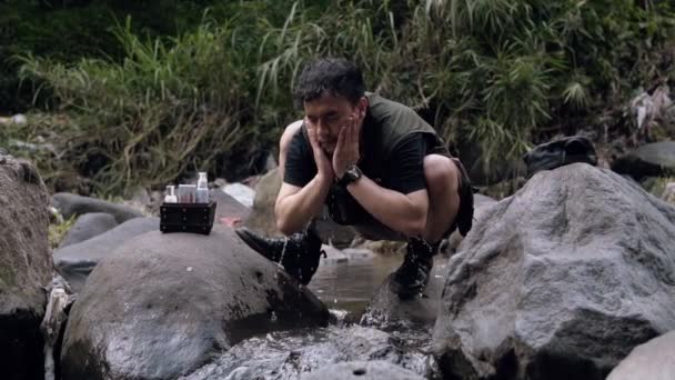 Asiatisk Man Tvättar Sitt Ansikte Med Flodvatten Mellan Stora Stenar — Stockvideo