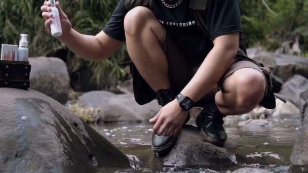 森の中の大きな岩の間の川の水で顔を洗っているアジアの男 — ストック動画