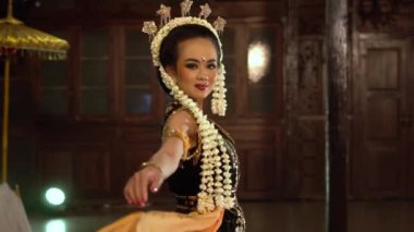 Geleneksel elbiseli bir Asyalı dansçı ahşap bir evde çok güzel poz veriyor.