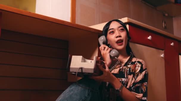 一个亚洲女人白天靠在厨房的橱柜上 一边用固定电话给男朋友打电话 — 图库视频影像
