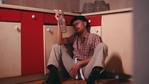 一个亚洲人 晚上在厨房里一边拿着杯子和瓶子一边凝视着 — 图库视频影像