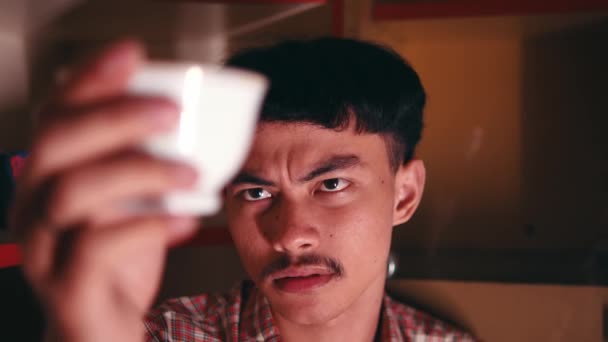 Hombre Asiático Sosteniendo Una Taza Una Botella Mientras Mira Atentamente — Vídeo de stock