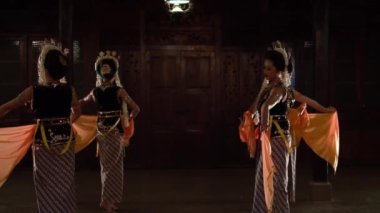 Bir grup siyah kostümlü Javalı dansçı akşam gösterisi boyunca birlikte dans ediyorlar.