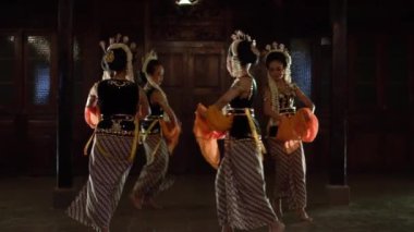 Bir grup siyah kostümlü Javalı dansçı akşam gösterisi boyunca birlikte dans ediyorlar.