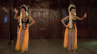 Sarı şallı bir grup Balili dansçı bir binada arkadaşlarıyla yavaşça dans ediyor.