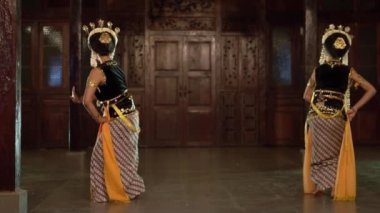 Sarı şallı bir grup Balili dansçı bir binada arkadaşlarıyla yavaşça dans ediyor.