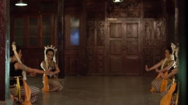 Sarı şallı bir grup Balili dansçı bir binada arkadaşlarıyla yavaşça dans ediyor.
