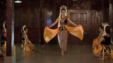 Sarı şallı bir grup Balili dansçı bir binada arkadaşlarıyla yavaşça dans ediyor.