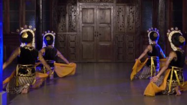 Bir grup Balili dansçı gece sahnede sarı şallarla dans ediyor.