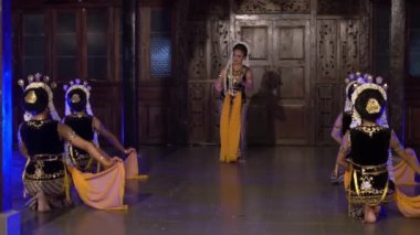 Bir grup Endonezyalı dansçı gece sahnede mavi ışıkla dans ediyor.