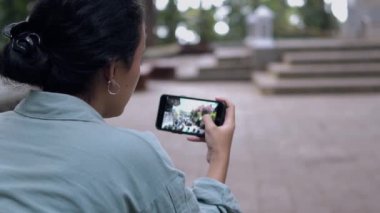 Asyalı bir kadın sabah kafede otururken elinde akıllı bir telefona bakıyor.