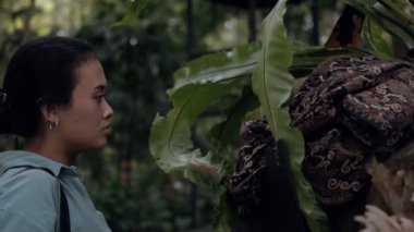 Ormanın ortasında kırmızı bir maske takan Asyalı bir kadın.