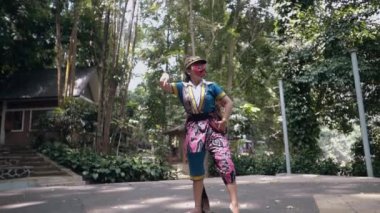 Şapka ve dans kostümü giymiş Endonezyalı bir dansçı öğle vakti elleri sahnenin ortasında dans eder.