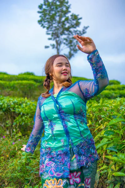 正午に茶園の間に立っている青い農民服のアジア人女性 — ストック写真