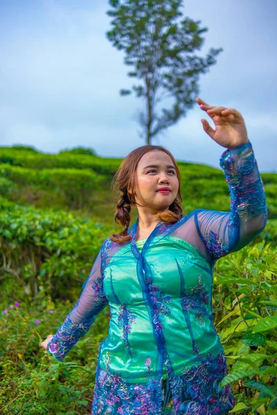 正午に茶園の間に立っている青い農民服のアジア人女性 — ストック写真