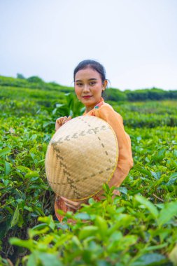 Cava 'lı bir kadın sabah turuncu bir elbise giydiğinde çay bahçesiyle ilgileniyor.