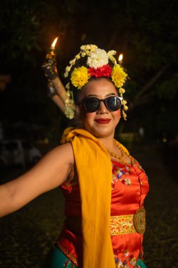 Geleneksel bir Cava dansçısı geceleri güneş gözlüğü takarken esnek bir vücutla dans eder.