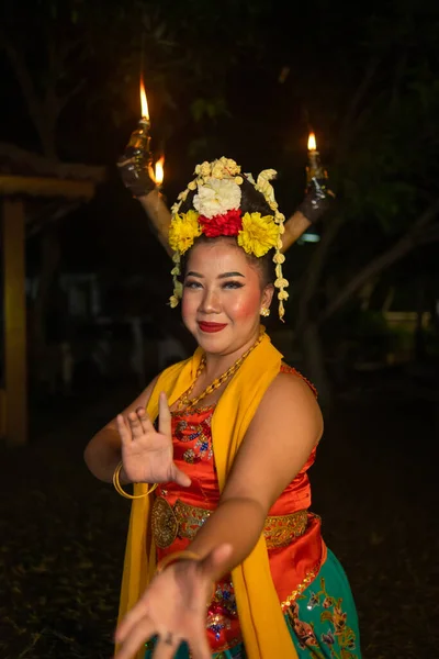 一个传统的爪哇舞蹈家在晚上的舞台上手握五彩缤纷的花朵跳舞 — 图库照片