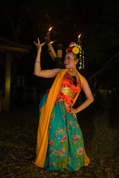 一位传统的亚洲舞蹈家穿着橙色服装 在燃烧的火炬前摆姿势 — 图库照片