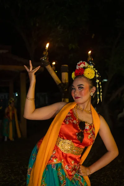 伝統的なアジアのダンサーは夜に非常に美しいオレンジ色の衣装で燃えるトーチの前にポーズします — ストック写真