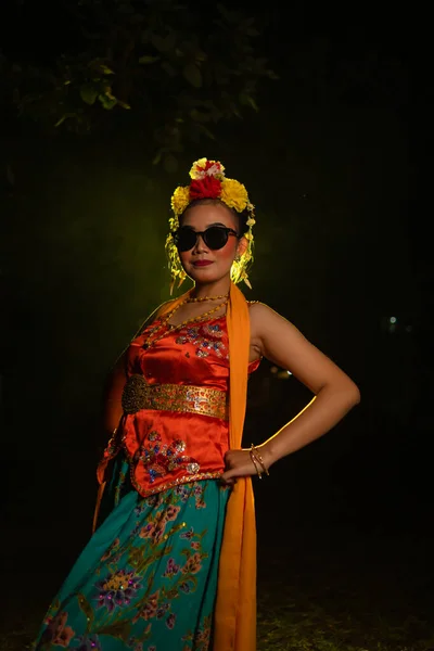 サングラスと夜の彼女の頭の上の花とオレンジのコスチュームを身に着けながら 輝く光の前で踊るスージーダンサー — ストック写真