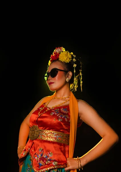 サングラスと夜の彼女の頭の上の花とオレンジのコスチュームを身に着けながら 輝く光の前で踊るスージーダンサー — ストック写真