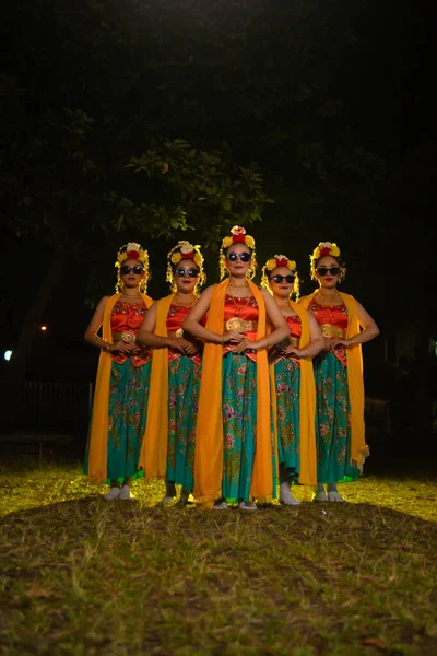 一群身着服装 头戴橙色披肩 戴着太阳镜的传统爪哇舞蹈家晚上都站在他们的面前 — 图库照片
