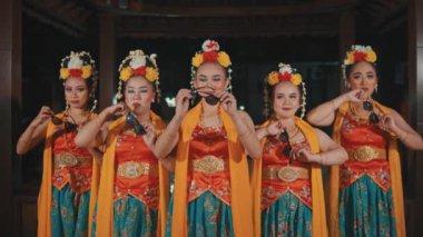 Geleneksel kostümlü beş kadın Cava dansçısı gece bir araya gelip, yüzlerine güneş gözlüğü doğrultarak kültürel kıyafetlerini modern ve havalı bir aksesuarla harmanlıyorlar..