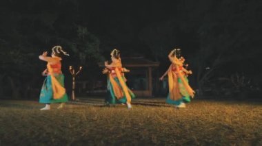 Bir grup geleneksel Sundanlı dansçı geceleri sarı kostümlü boş bir tarlada dans ediyor.