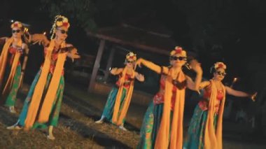 Geleneksel kostüm ve modern güneş gözlüğü takan Endonezyalı bir grup kadın dansçının orta ölçekli fotoğrafı. Geceleri bambu alev meşaleleriyle aydınlatılan senkronize kültürel bir dans yapıyorlar..