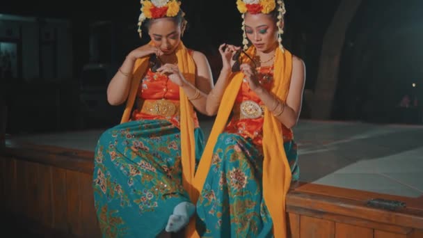Kilku Indonezyjskich Tancerzy Tradycyjnych Pomarańczowych Kostiumach Siedzi Przyjaciółmi Pawilonie Nocy — Wideo stockowe