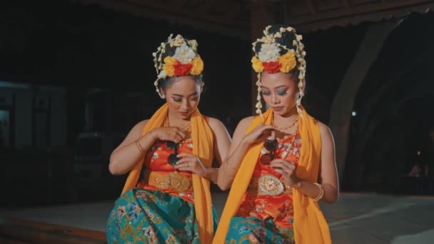 几个身穿橙色服装的印尼传统舞蹈家晚上和他们的朋友一起坐在亭子里 — 图库视频影像