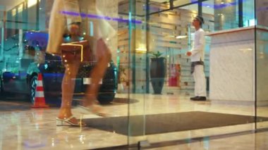 Aydınlık ve lüks bir otel lobisinde yürüyen şık bir kadının bacakları ve el çantasına odaklanmış yan görüntü görüntüsü..