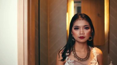 Kalın makyajlı, kameraya yoğun bir şekilde bakan ve yüzünün yarısını kaplayan beyaz bir kapı gibi yüzünü yavaşça gizleyen güzel bir kadının aşırı yakın çekimi..