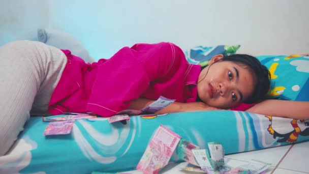 一个亚洲女人 她悲伤而焦虑 早上躺在地板上 满地都是零用钱 — 图库视频影像
