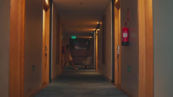 ホテルの訪問者は夜に部屋を探している黄色いライトでいっぱいの廊下を歩きます — ストック動画